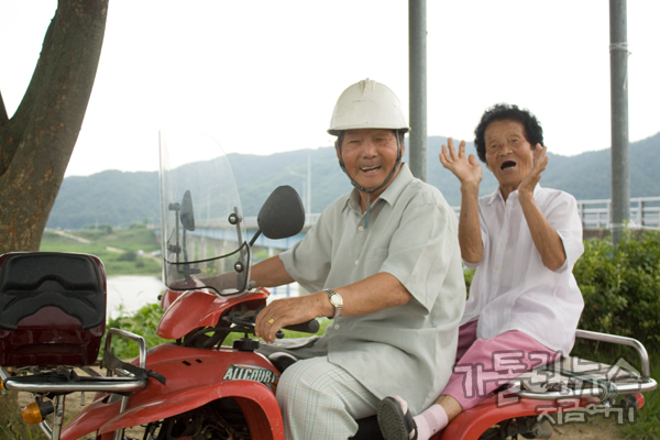 4륜 오토바이를 몰고 지나가다 아이들을 응원하는 할아버지, 할머니.