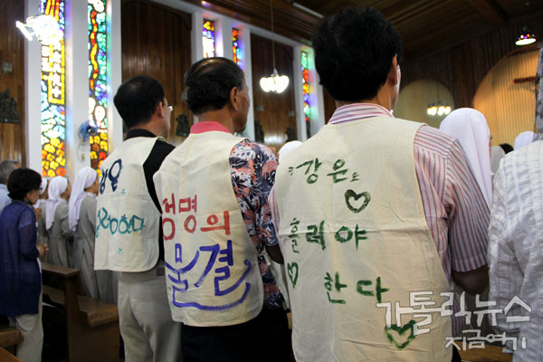 '강은 흘러야 한다'라는 몸자보를 걸치고 미사에 참석한 신자(사진/ 고동주 기자)