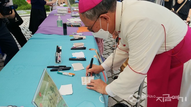 농민주일 미사를 집전한 구요비 주교가 농민들을 응원하는 메시지를 쓰고 있다. ⓒ배선영 기자<br>