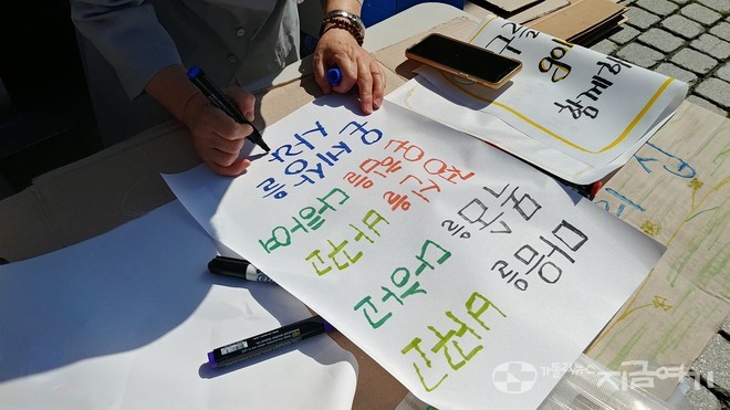 한 수도자가 피조물 보호를 위한 기도의 날 행진에서 들기 위해 기후위기를 알리는 문구를 적고 있다. ⓒ배선영 기자<br>