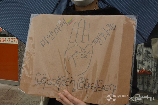 미얀마 민주주의를 위한 미사에서 한 신자가 '미얀마의 평화를'라고 한국어와 미얀마어로 써진 푯말을 듣고 있다. 군부 쿠데타에 대한 저항을 뜻하는 세 손가락 표시가 가운데 그려져 있다. ⓒ배선영 기자<br>