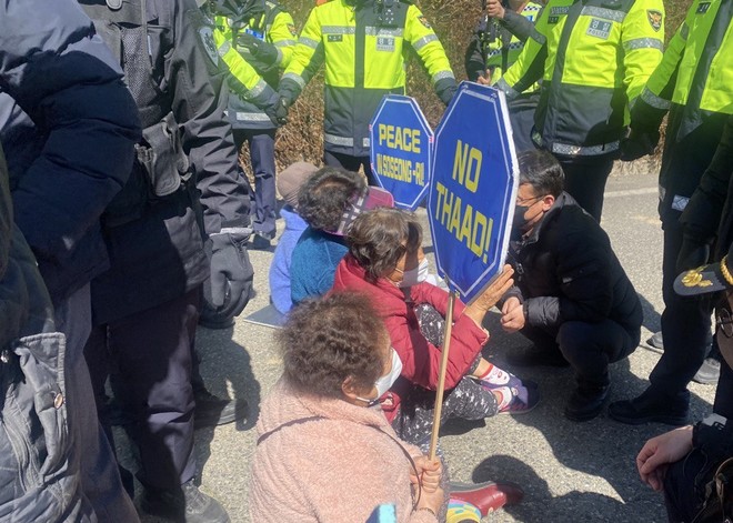 "NO THADD”가 적힌 손팻말을 들고 있는 소성리 할머니들이 경찰들에 둘러싸여 있다. (사진 제공 = 서울대교구 정의평화위원회)