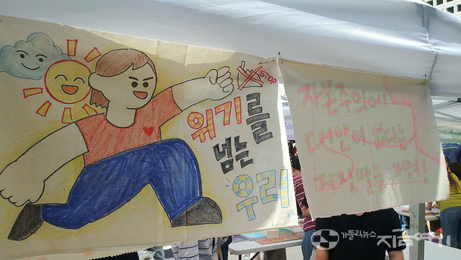 923 기후정의행진 부스에서 걸린 그림과 글. '위기를 넘는 우리', '자본주의에 대안이 없다는 거짓말을 버려!'라고 쓰여 있다. ⓒ배선영 기자<br>