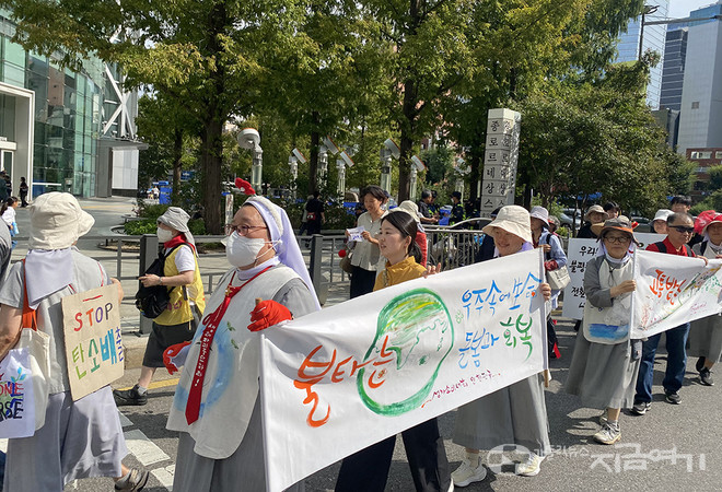 수도자와 참가자들이 ‘멈춰, 탄소배출’ 손팻말과 ‘불타는 우주 속에 생명 돌봄과 회복’ 현수막을 들고 행진하고 있다. ⓒ정현진 기자